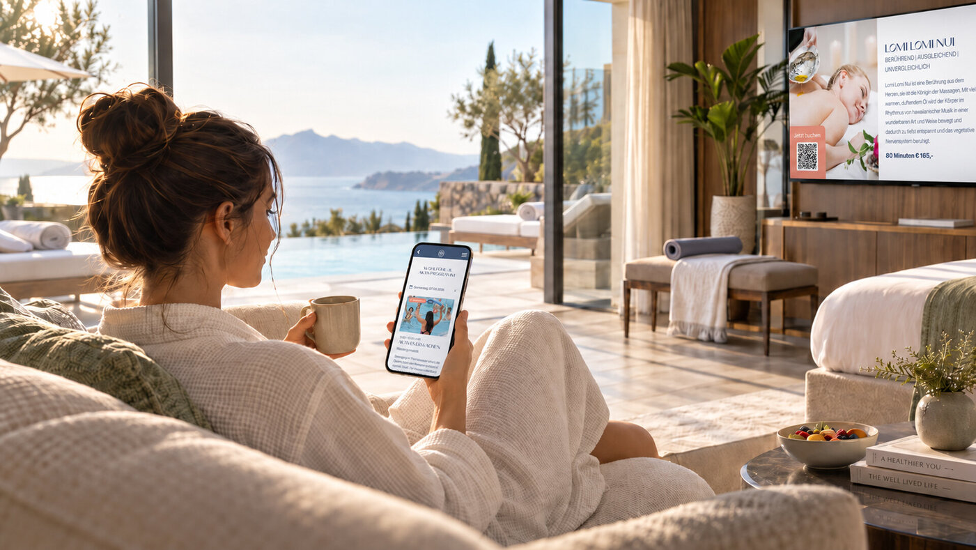 Longevity im Hotel Eine Dame, die im Hotelzimmer mit Aussicht auf der Couch sitzt, und auf dem Handy sowie dem TV die Wellnessangebote checkt