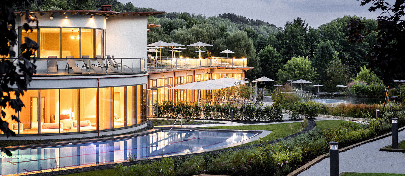 Abendaufnahme der beleuchteten Heiltherme Bad Waltersdorf mit Pool und Grünanlage